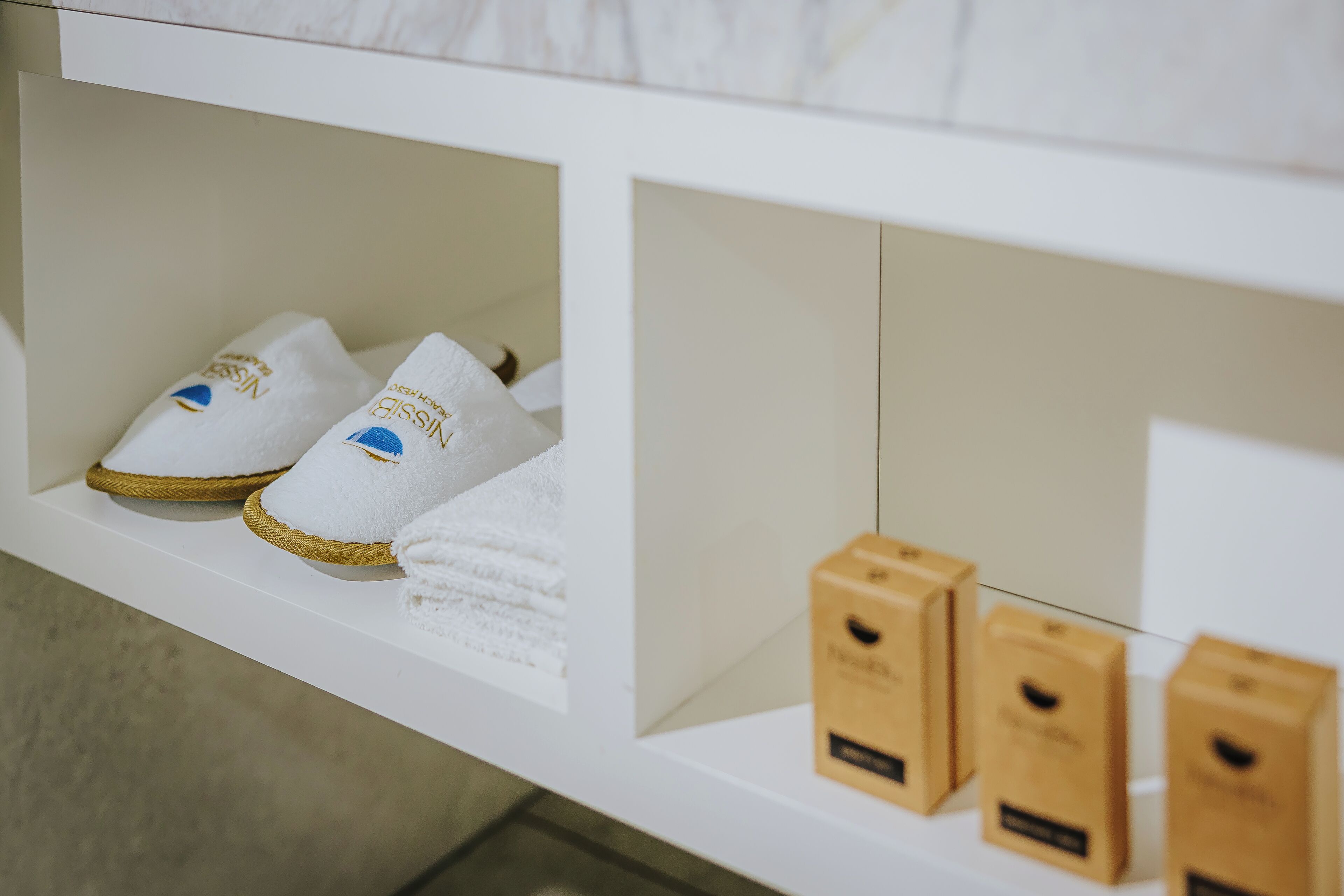 A white shelf with slippers and boxes.