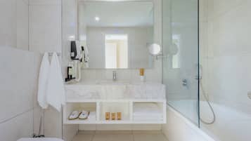 Un baño moderno con ducha de vidrio, un espejo grande y tocador de mármol.