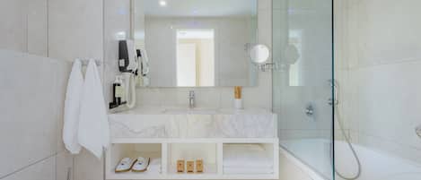 A modern bathroom with a glass-enclosed shower, a large mirror, and a marble vanity.