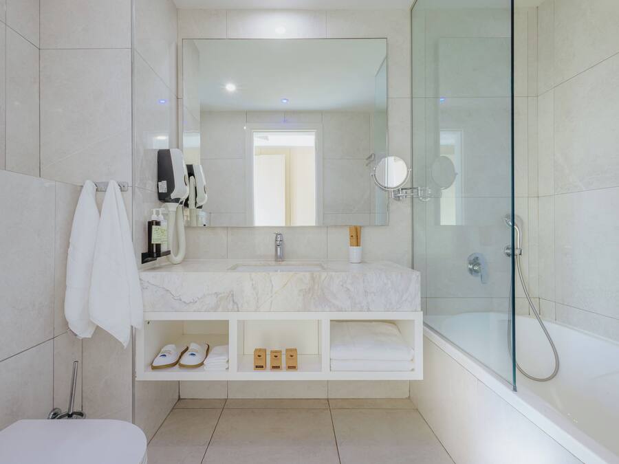 Un baño moderno con ducha de vidrio, un espejo grande y tocador de mármol.