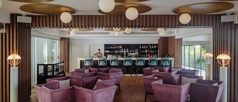 A bar area with purple seating, a bar counter, and a modern ceiling design.