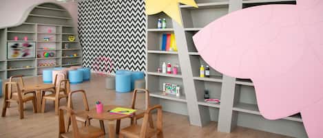 A children's playroom with wooden furniture, colorful storage units, and a chevron-patterned wall.