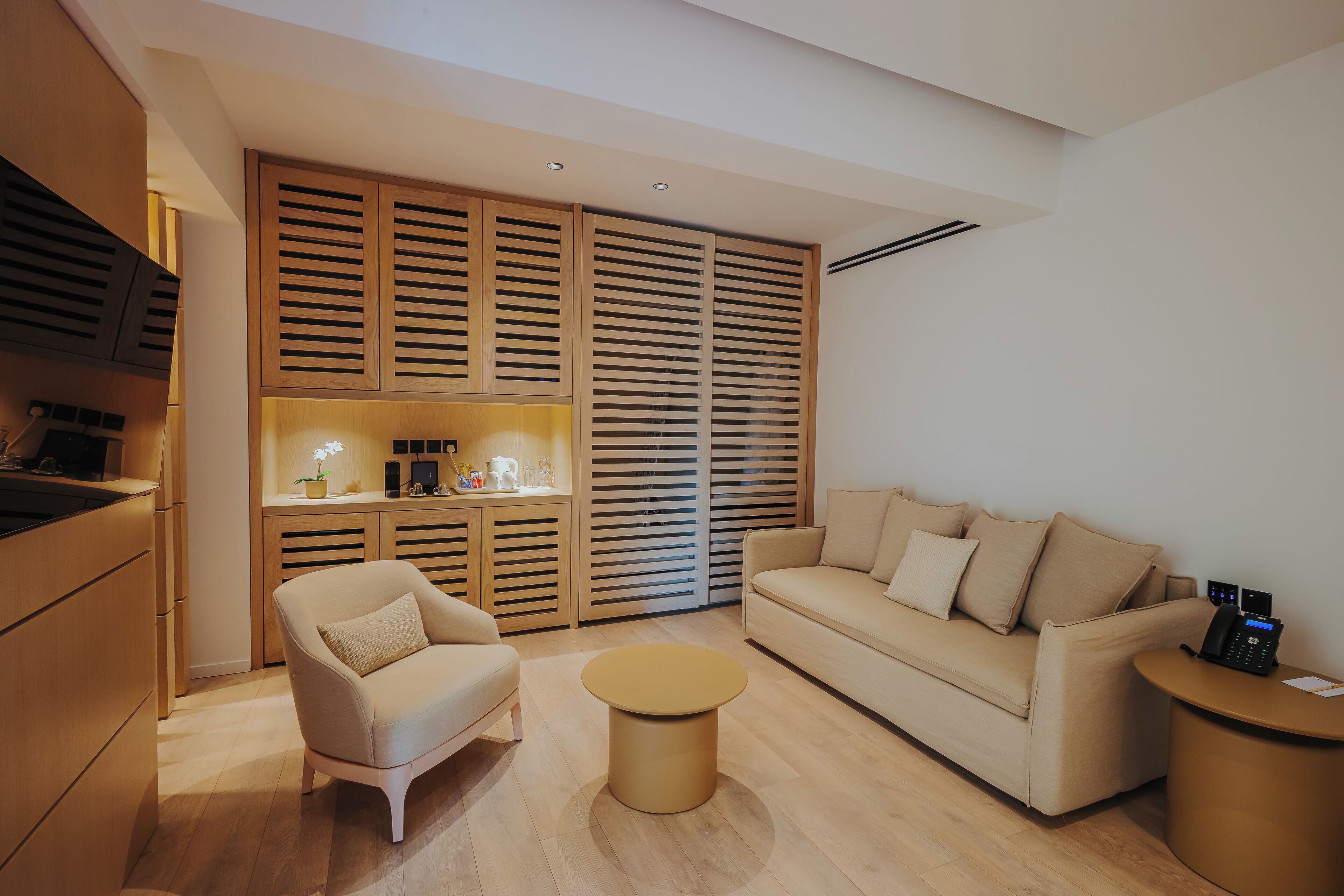 A modern living room with a sofa, armchair, coffee table, and built-in wooden shelving.