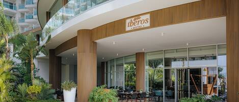 A modern bistro with outdoor seating, large windows, and a sign reading 'theros BISTRO.'