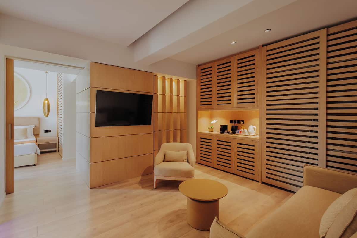 Uma sala de estar moderna com televisão de tela plana, sofá, mesa de centro redonda e painéis de madeira.