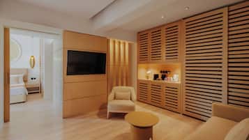Una sala de estar moderna con un televisor de pantalla plana, un sofá, una mesa de centro redonda y paneles de madera.