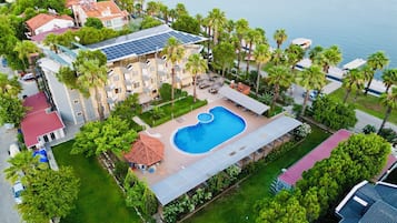 Surrounded by lush greenery and palm trees, this resort features a central pool and multiple buildings with balconies.