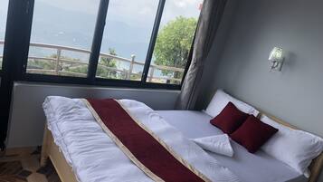 A hotel room with a large bed, a view of the sea, and a balcony.