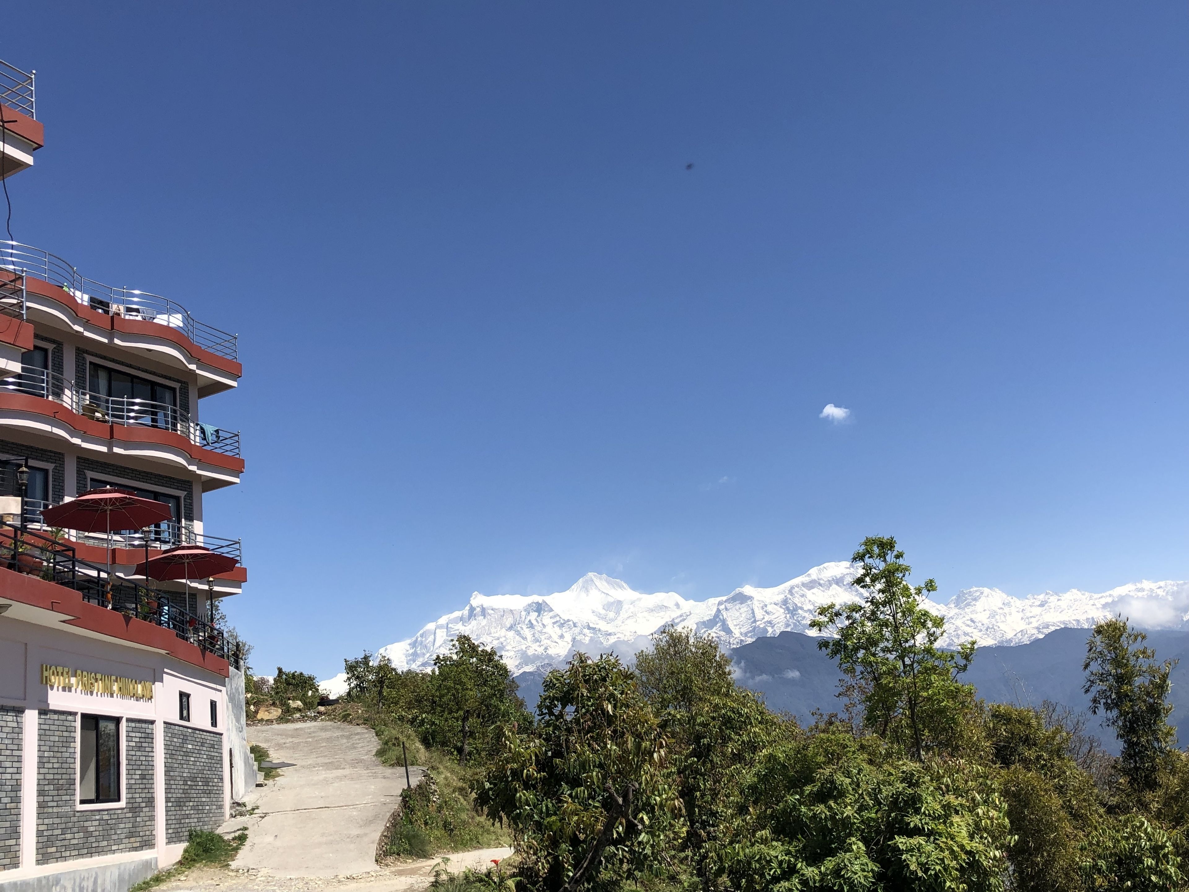C’est un hôtel à étages, doté de balcons et orné de parasols rouges. Il est situé à proximité de montagnes enneigées.