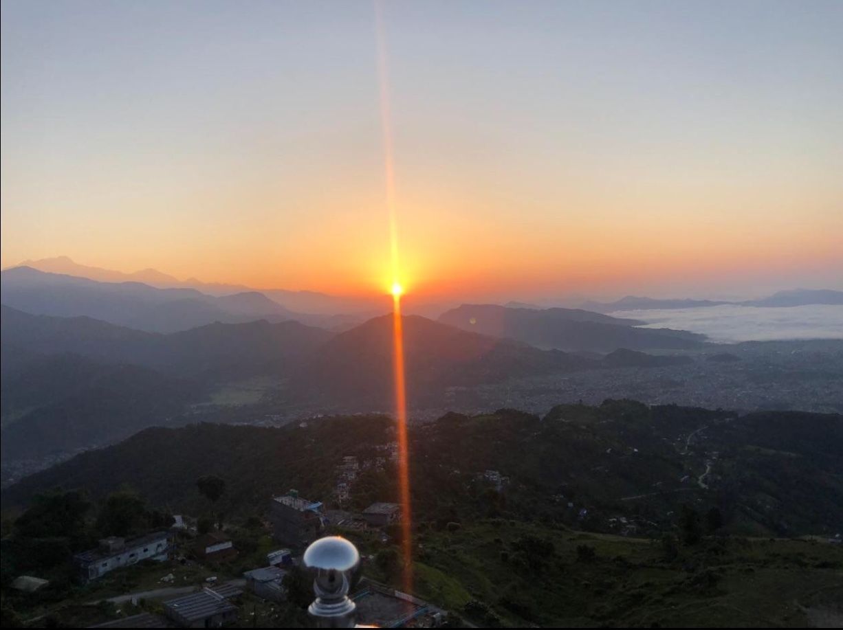 Amanecer sobre un paisaje montañoso con una casa visible y una antena parabólica.
