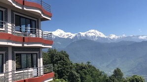 Ein mehrgeschossiges Gebäude mit Balkonen, einem wolkenlosen Himmel und einer Bergkette im Hintergrund.