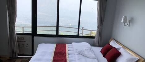 Een hotelkamer met een groot bed, uitzicht op de stad door het raam en een bordje dat de standaard van de kamer aangeeft.