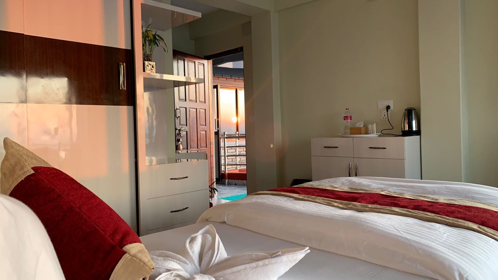 A hotel room with a bed, a wardrobe, a desk, and a view of the outside.