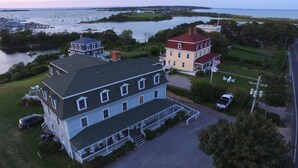 A large, multi-story building with a prominent porch and a flagpole. - Payne's Harbor View Inn (Block Island)