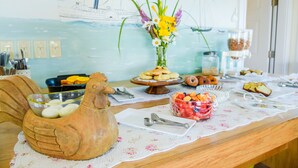 A breakfast buffet with various food items, a decorative ceramic rooster, and a wall mural. - Payne's Harbor View Inn (Block Island)