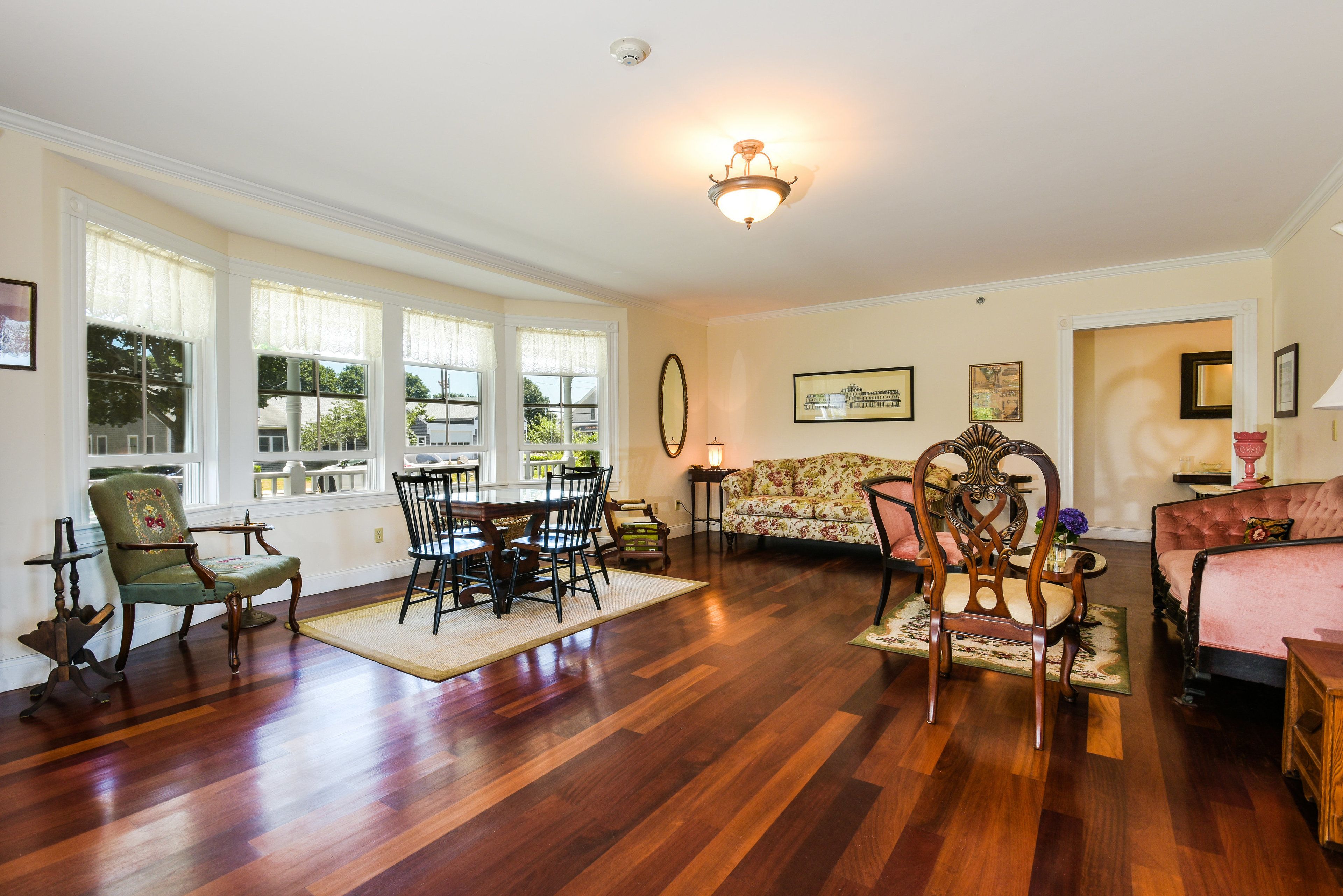 A spacious living room with hardwood flooring, a dining area with a table and chairs, a sofa, and a fireplace.