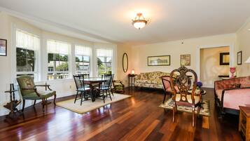 A spacious living room with hardwood flooring, a dining area with a table and chairs, a sofa, and a fireplace.