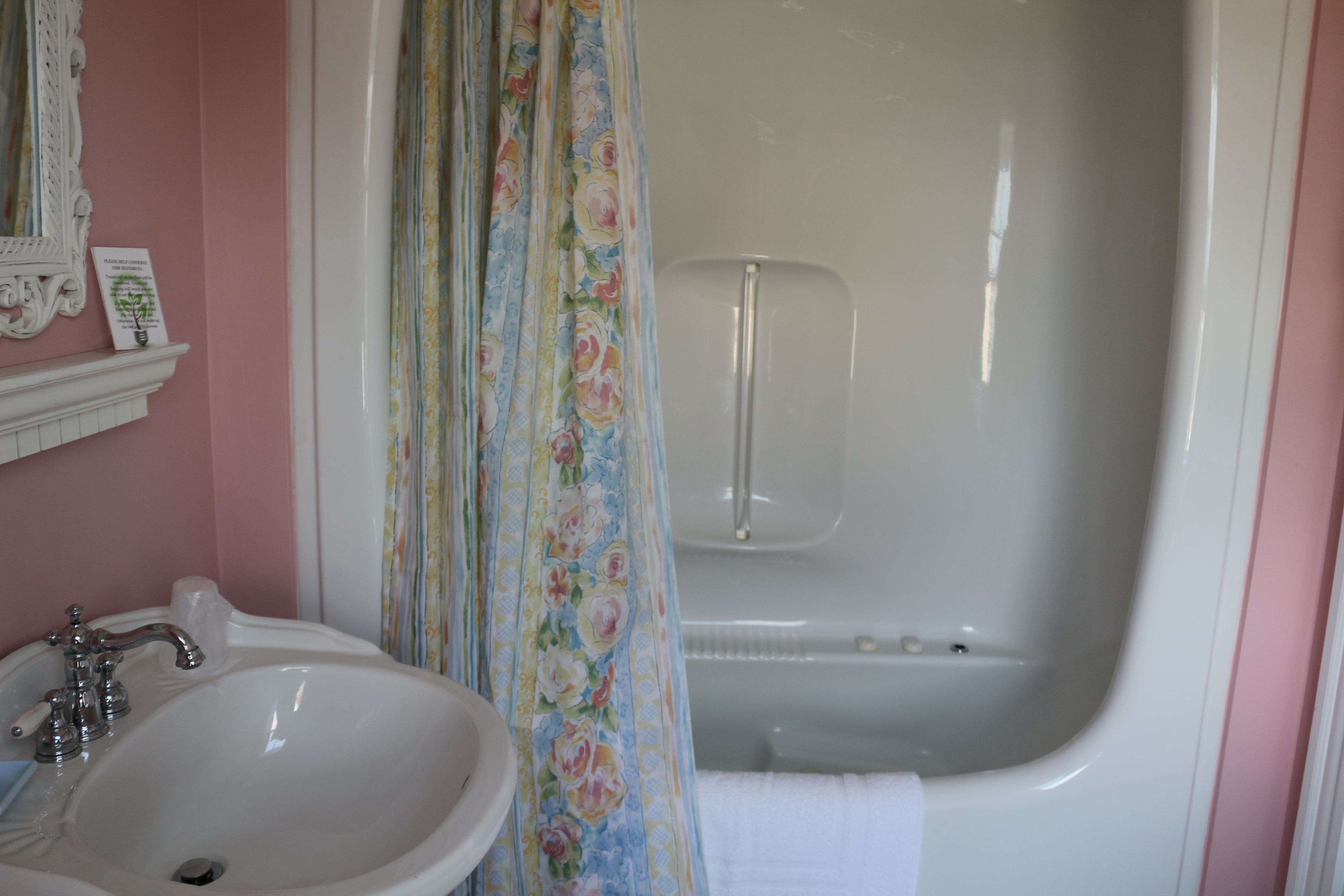 Een badkamer met een wastafel, spiegel en bad.