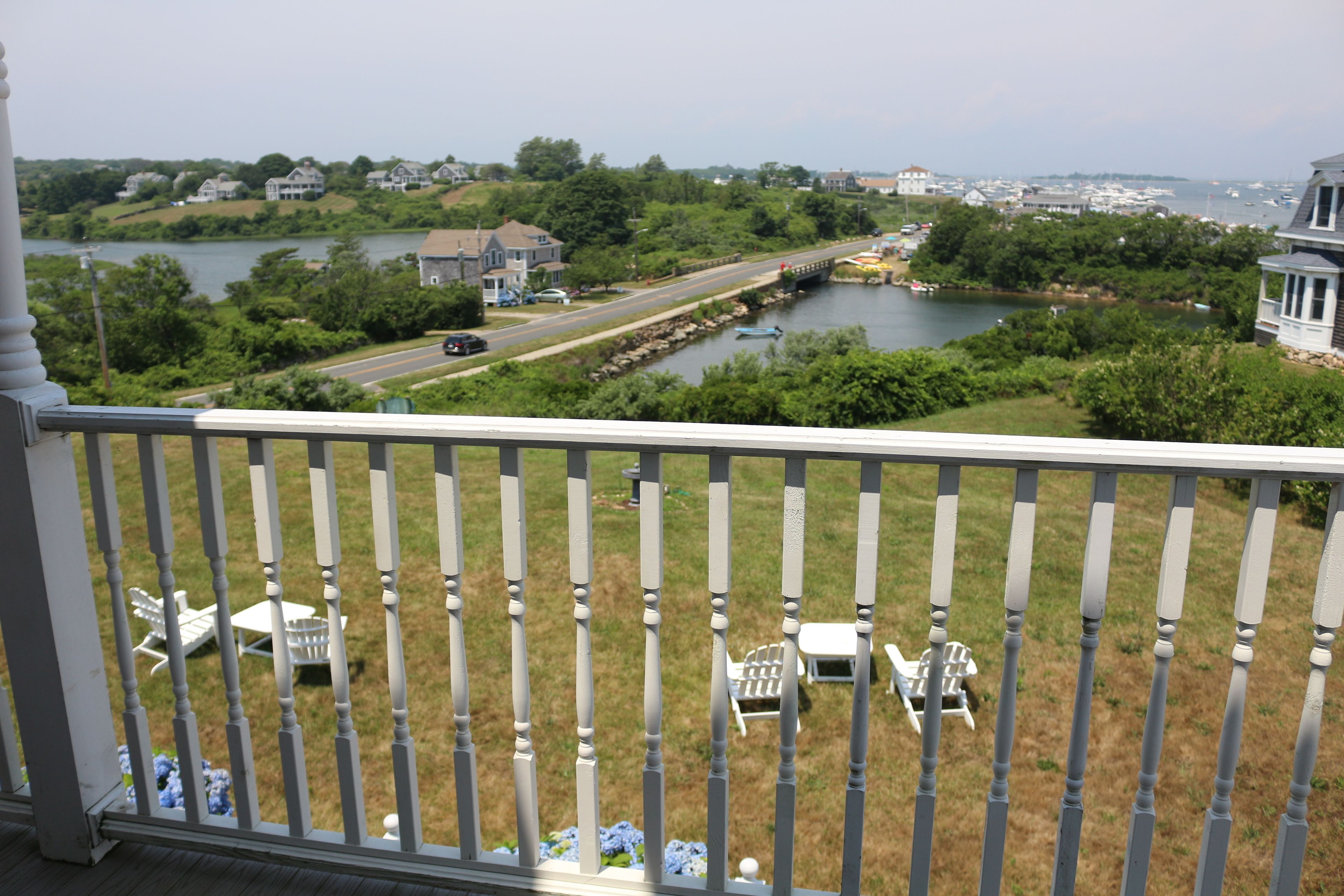 A balcony with a view of a river, houses, and a bridge.