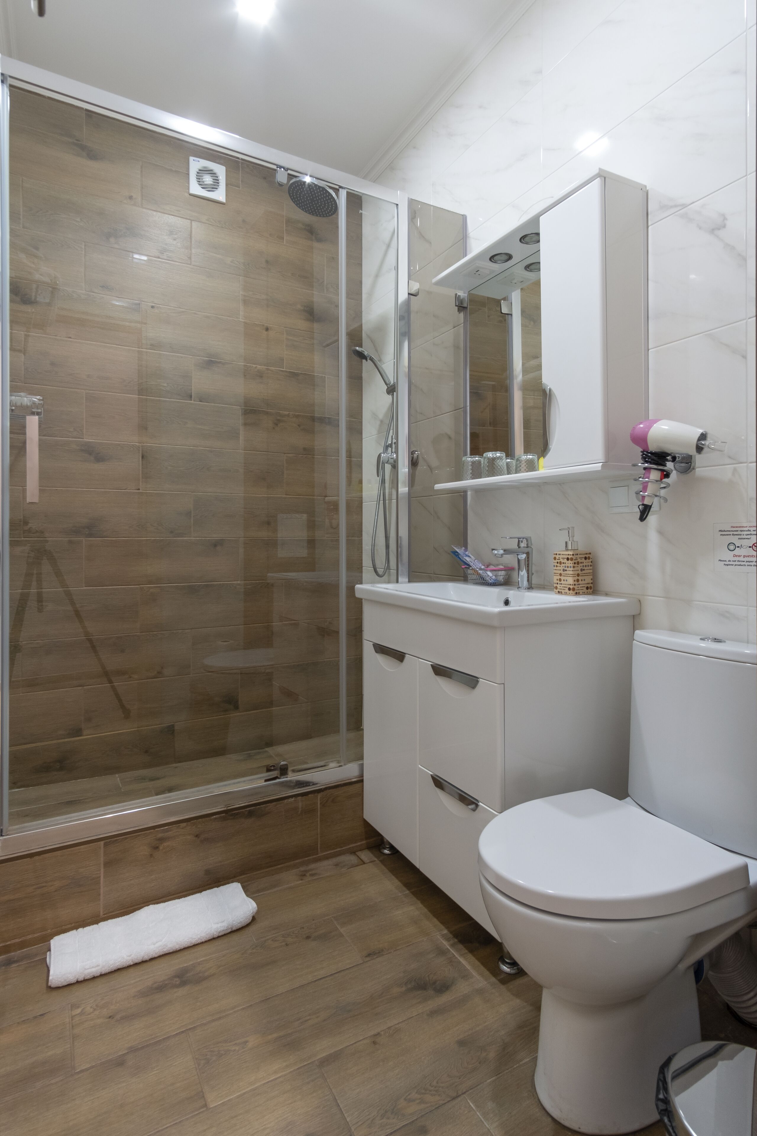 A bathroom with a glass-enclosed shower, a white toilet, and a vanity with a mirror.