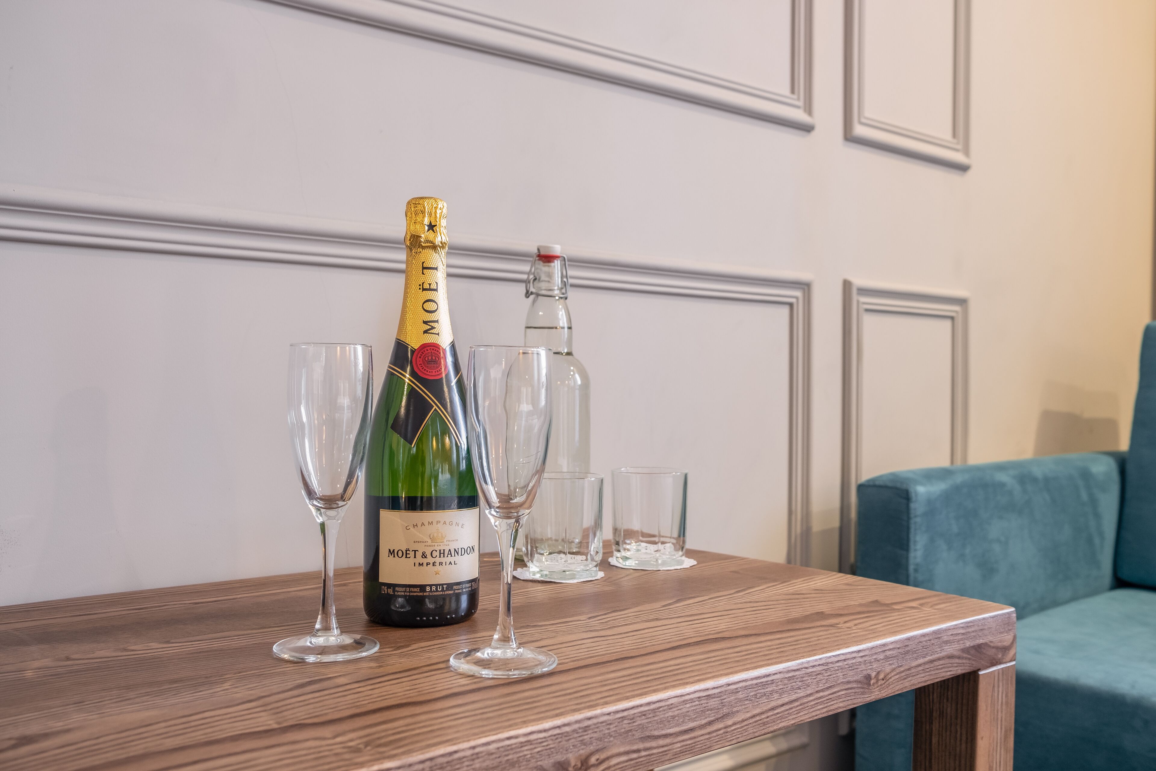 Une bouteille de champagne Moët & Chandon sur une table en bois, avec deux verres et une petite bouteille.
