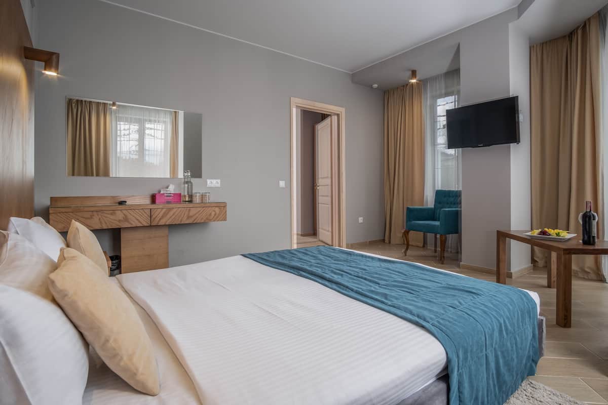 Een hotelkamer met een bed, een bureau met spiegel, een televisie en een stoel.