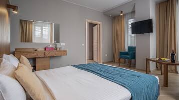 A hotel room with a large bed, a wooden dresser, a TV mounted on the wall, and a chair.