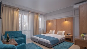 A modern bedroom with a large bed, a blue sofa, a wooden nightstand, and a desk with a vase.