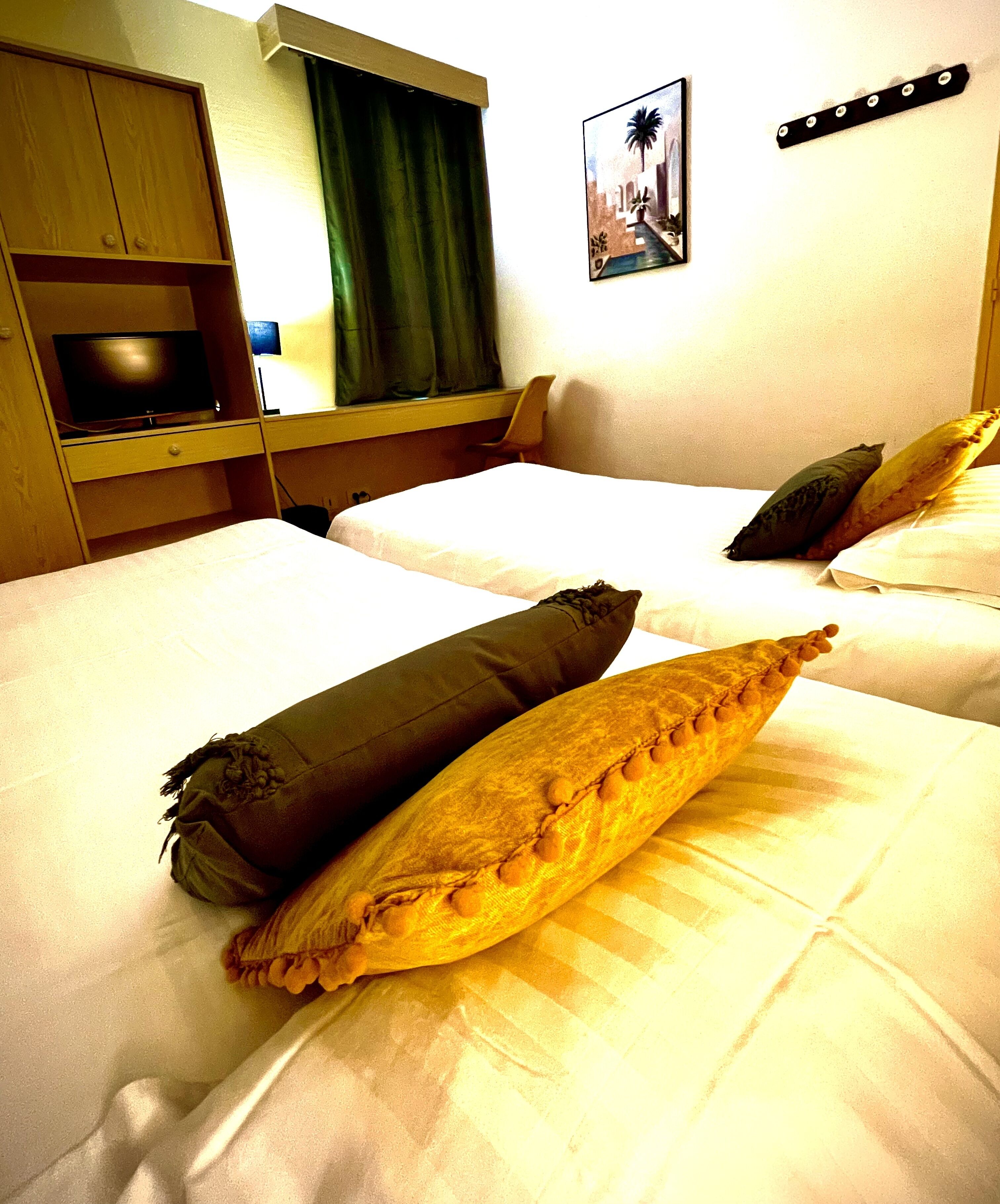 Una habitación de hotel con dos camas, cada una con una almohada y una mesita de noche.