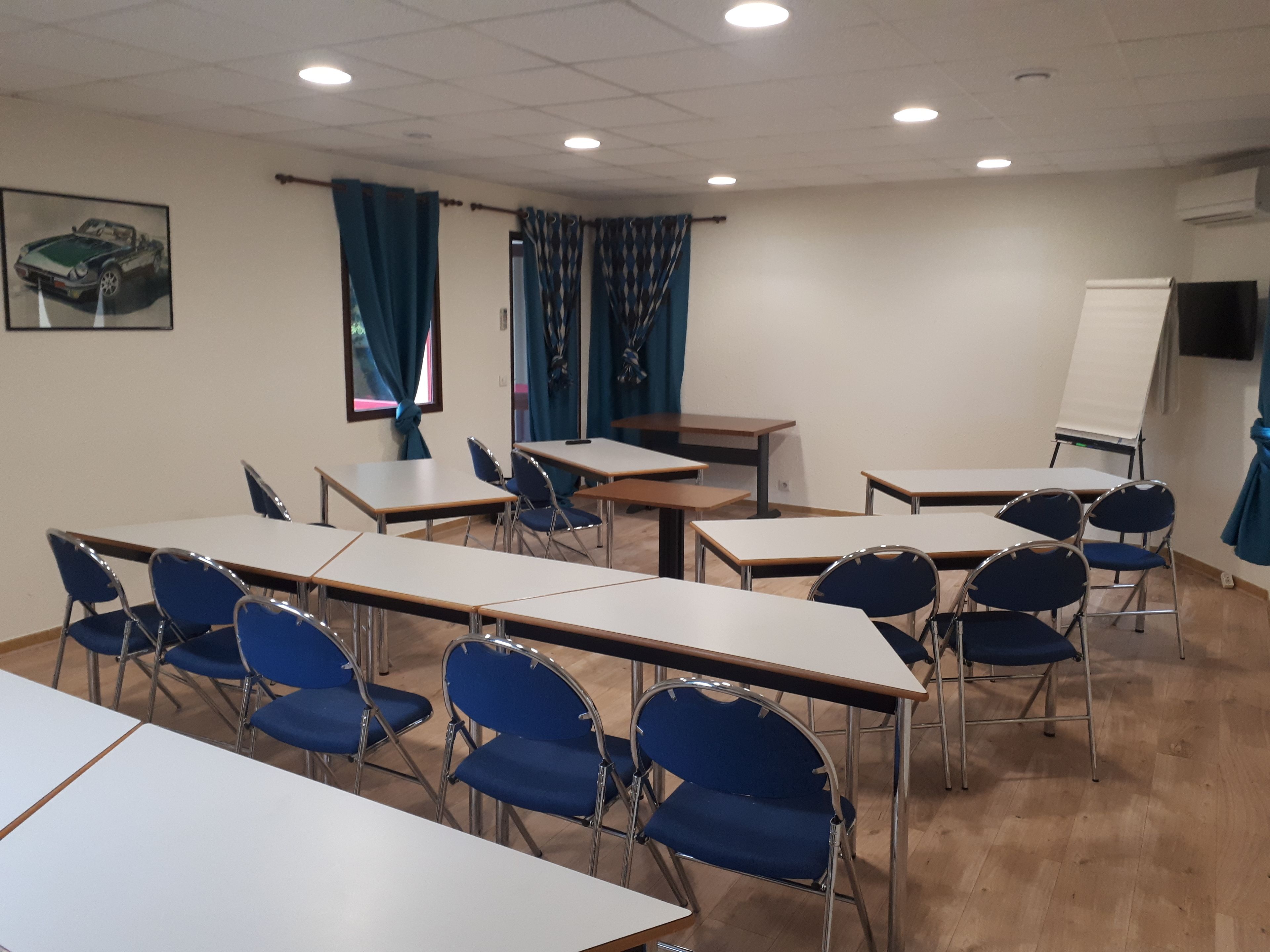 A classroom with desks and chairs, a whiteboard, and a painting on the wall.
