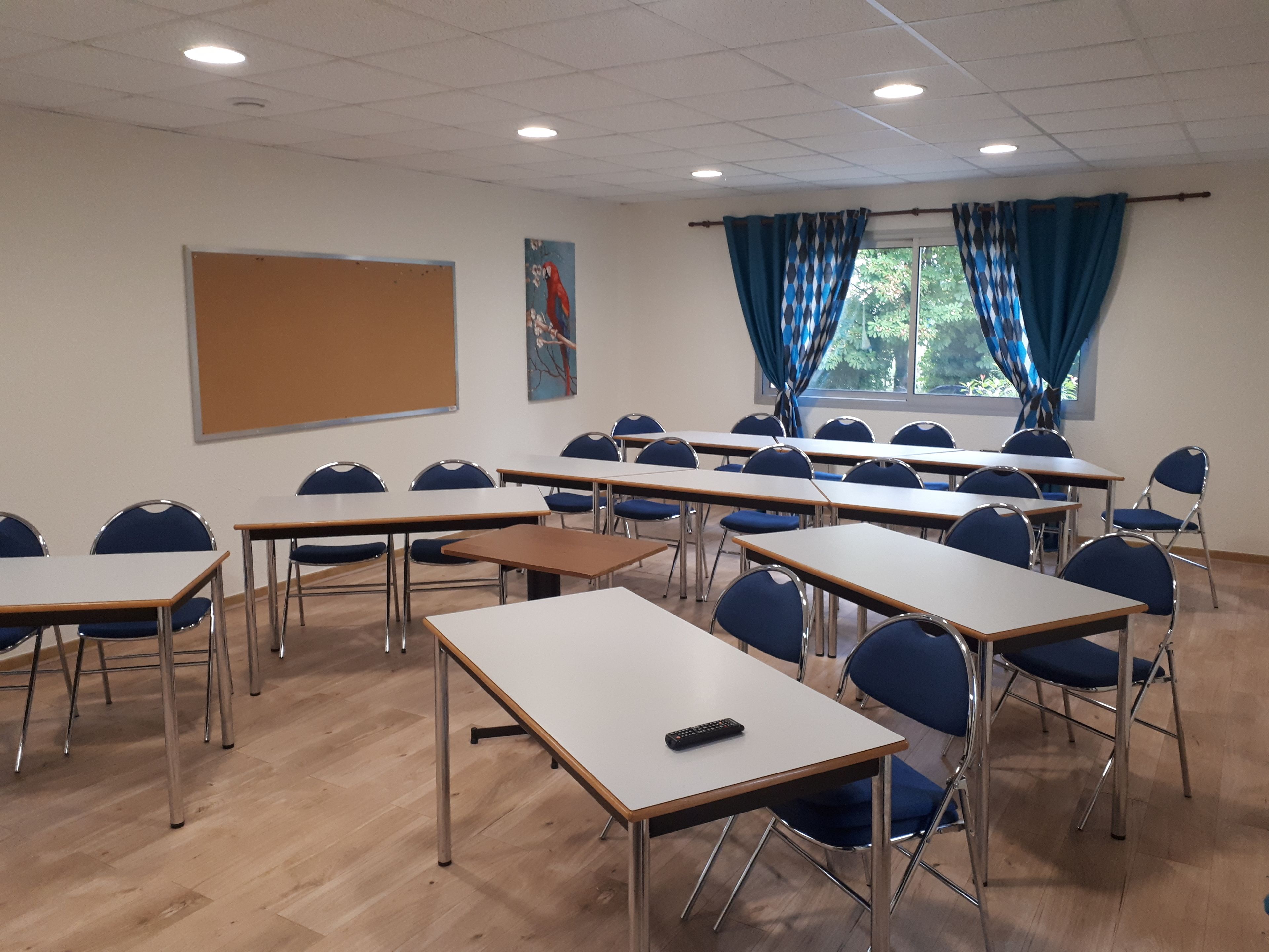 A classroom with rows of desks and chairs, a whiteboard, and a window with blue curtains.