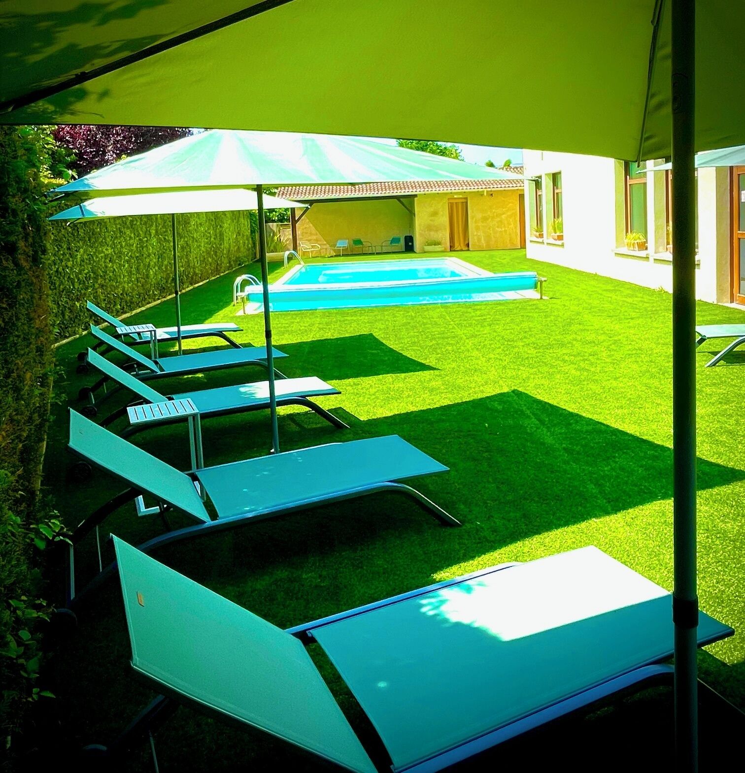 A poolside area with lounge chairs and a large umbrella.