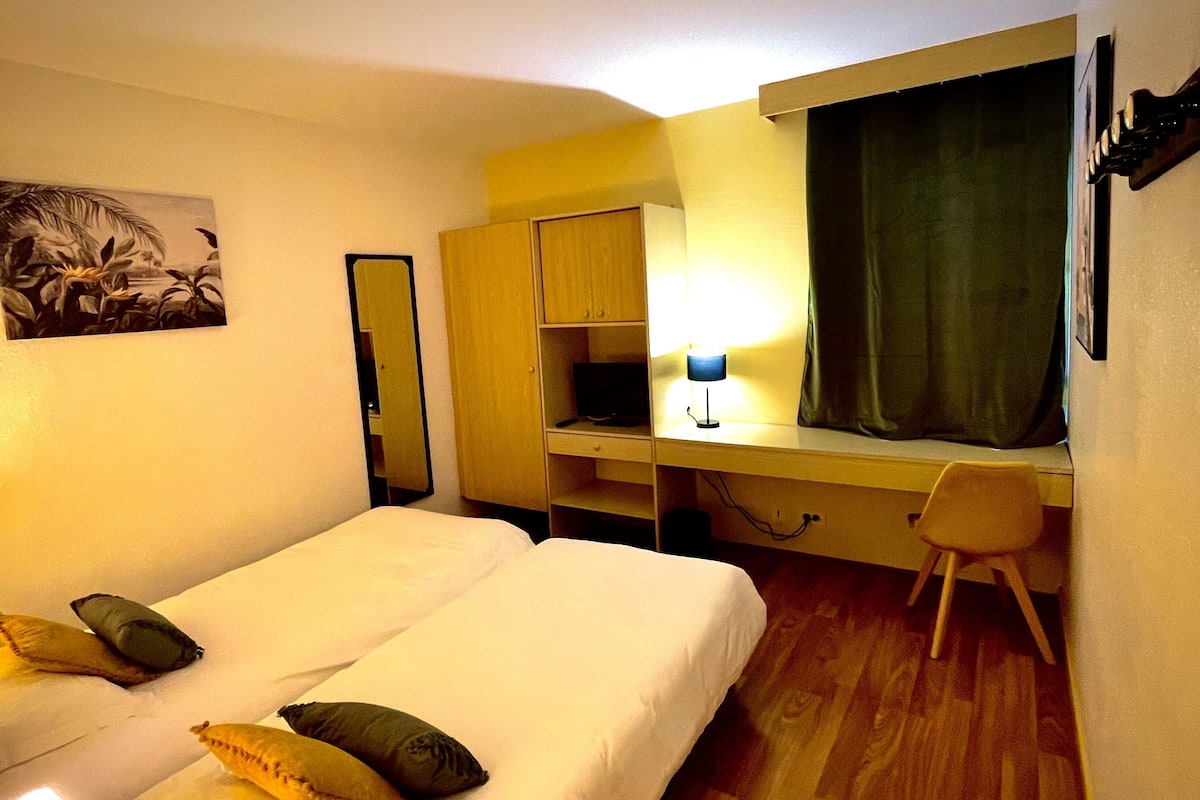 Une chambre d’hôtel avec un lit, un bureau, une chaise, une lampe et un tableau au mur.