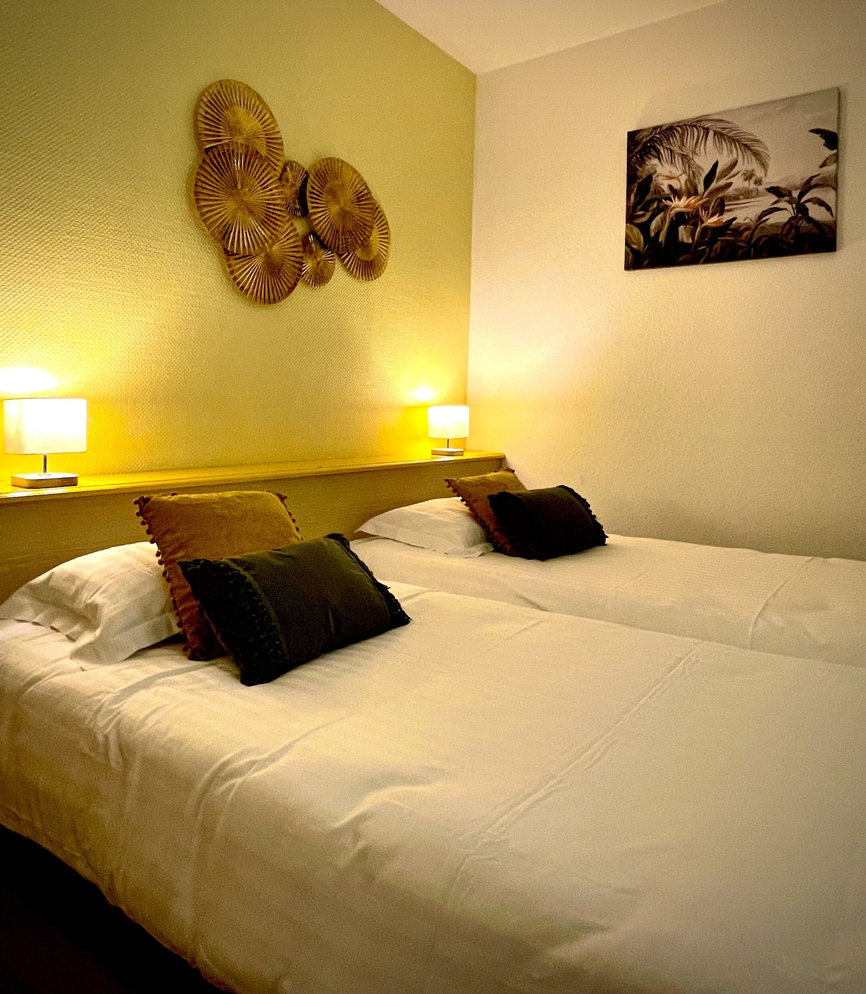 A hotel room with two beds, each with white linens and decorative pillows. There are two bedside lamps on the nightstands.