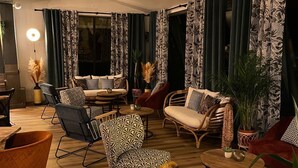A modern living room with a wooden floor, patterned sofas, and a variety of chairs. - Hôtel Restaurant Le Mont Brouilly (Quincie-en-Beaujolais)