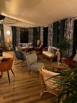 Una sala de estar moderna con piso de madera, sofás estampados y una variedad de sillones.