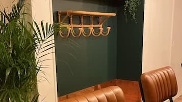A room with two brown leather chairs, a wooden floor, a green wall, and a shelf with decorative items.
