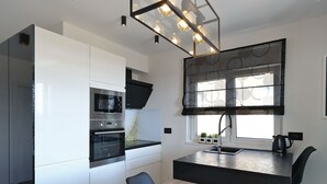 A modern kitchen with white cabinetry, a built-in oven, and a black countertop. - Luxury Majpruz Suites (Zadar)