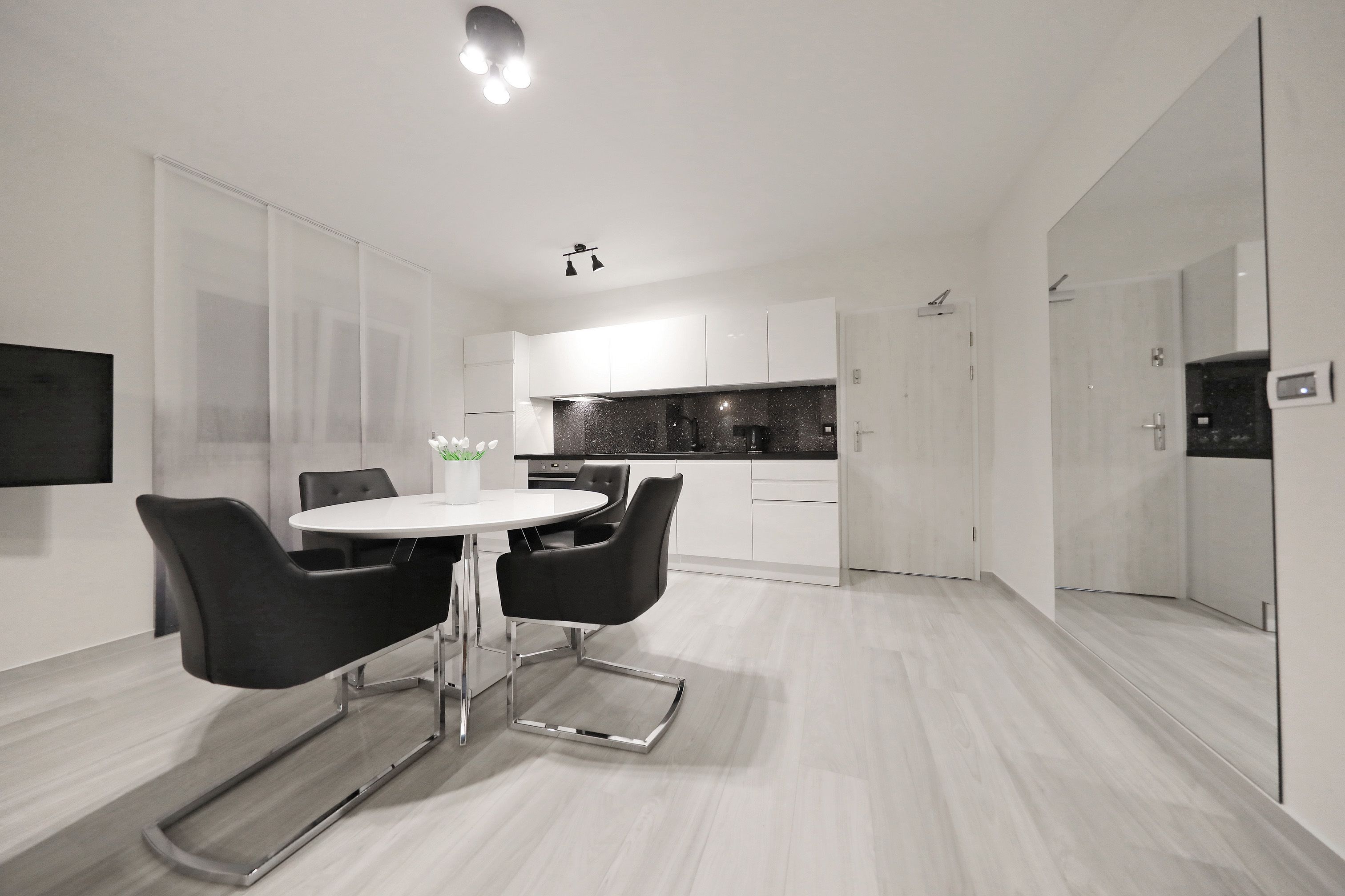 A modern kitchen with white cabinets, a black countertop, and a built-in oven.