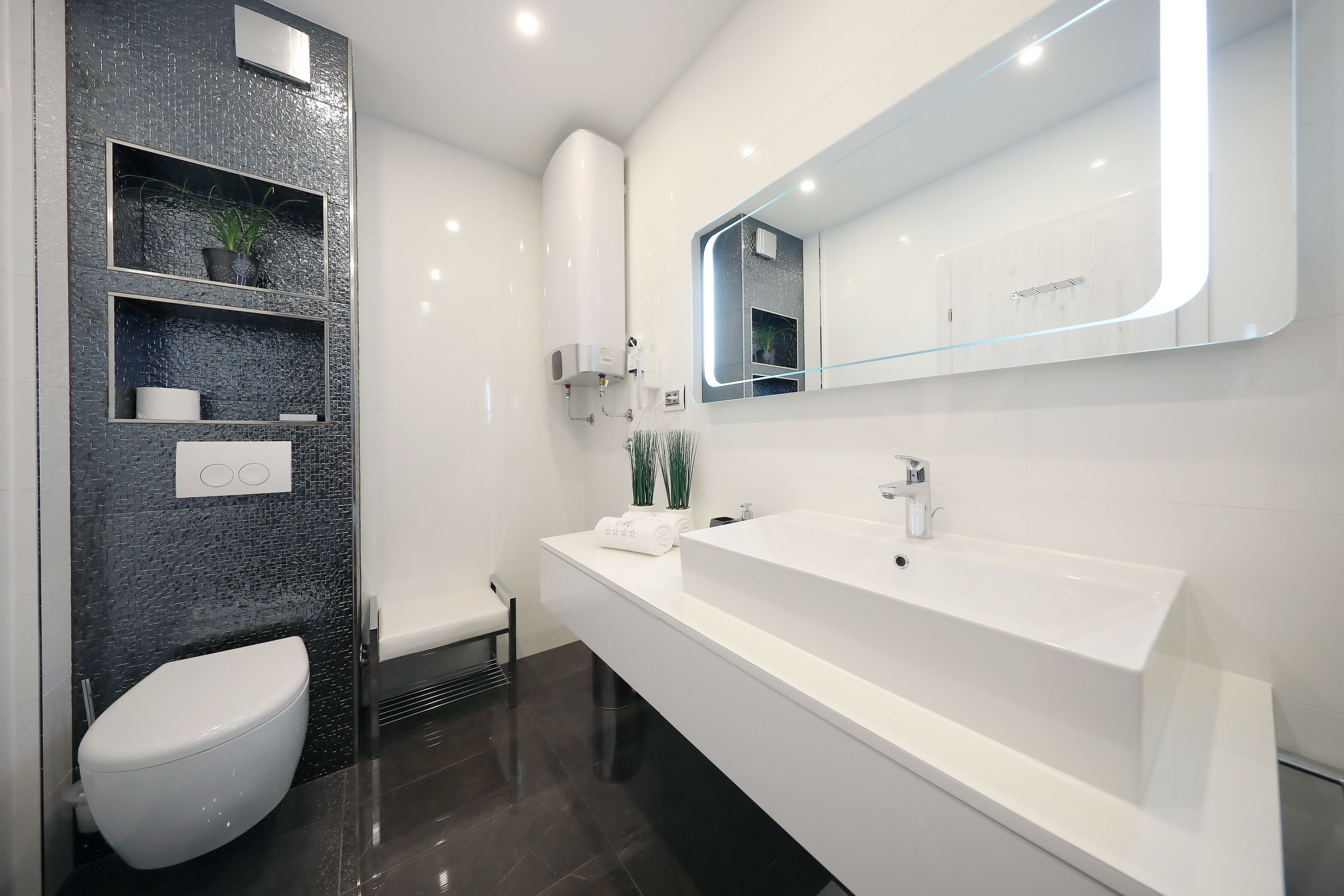 A modern bathroom with a white sink, a large mirror, and a toilet.
