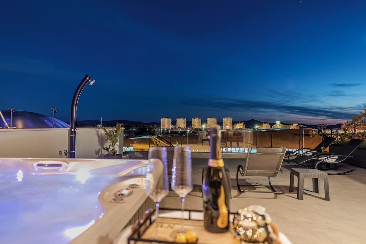 Terraço no telhado com hidromassagem, espreguiçadeiras e uma garrafa de champanhe.