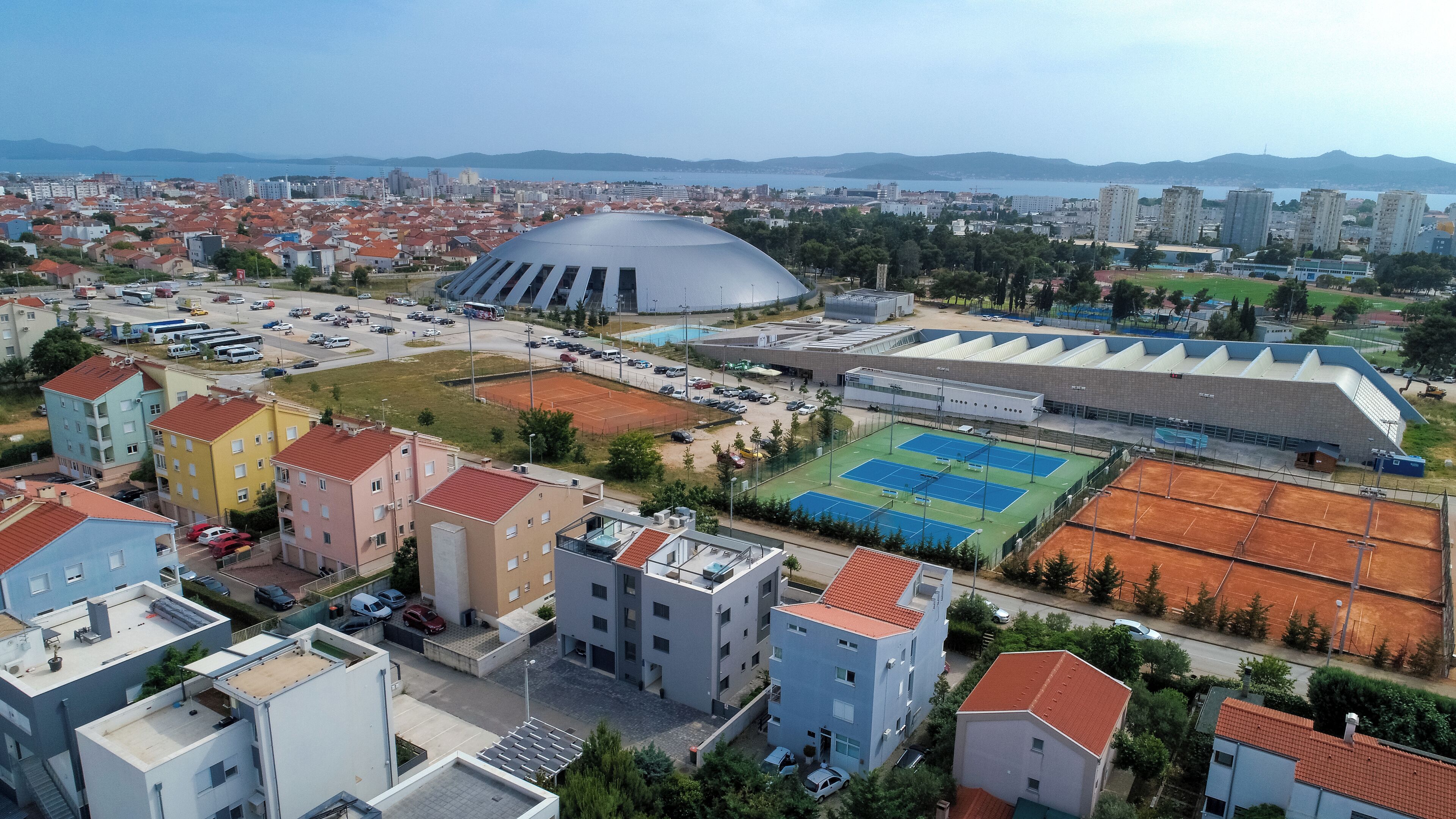 Ett flygbildsbild av en stadsbild med en stor stadion, bostadshus och ett sportkomplex.