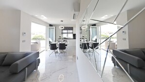 A modern hotel lobby with a marble floor, a seating area with sofas, a dining table with chairs, and large mirrors. - Luxury Majpruz Suites (Zadar)