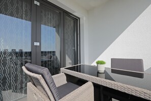 A balcony with wicker furniture, a glass table, and a potted plant. - Luxury Majpruz Suites (Zadar)