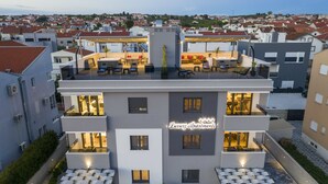 A modern building with multiple balconies, outdoor seating, and a sign reading "Luxury Apartments". - Luxury Majpruz Suites (Zadar)