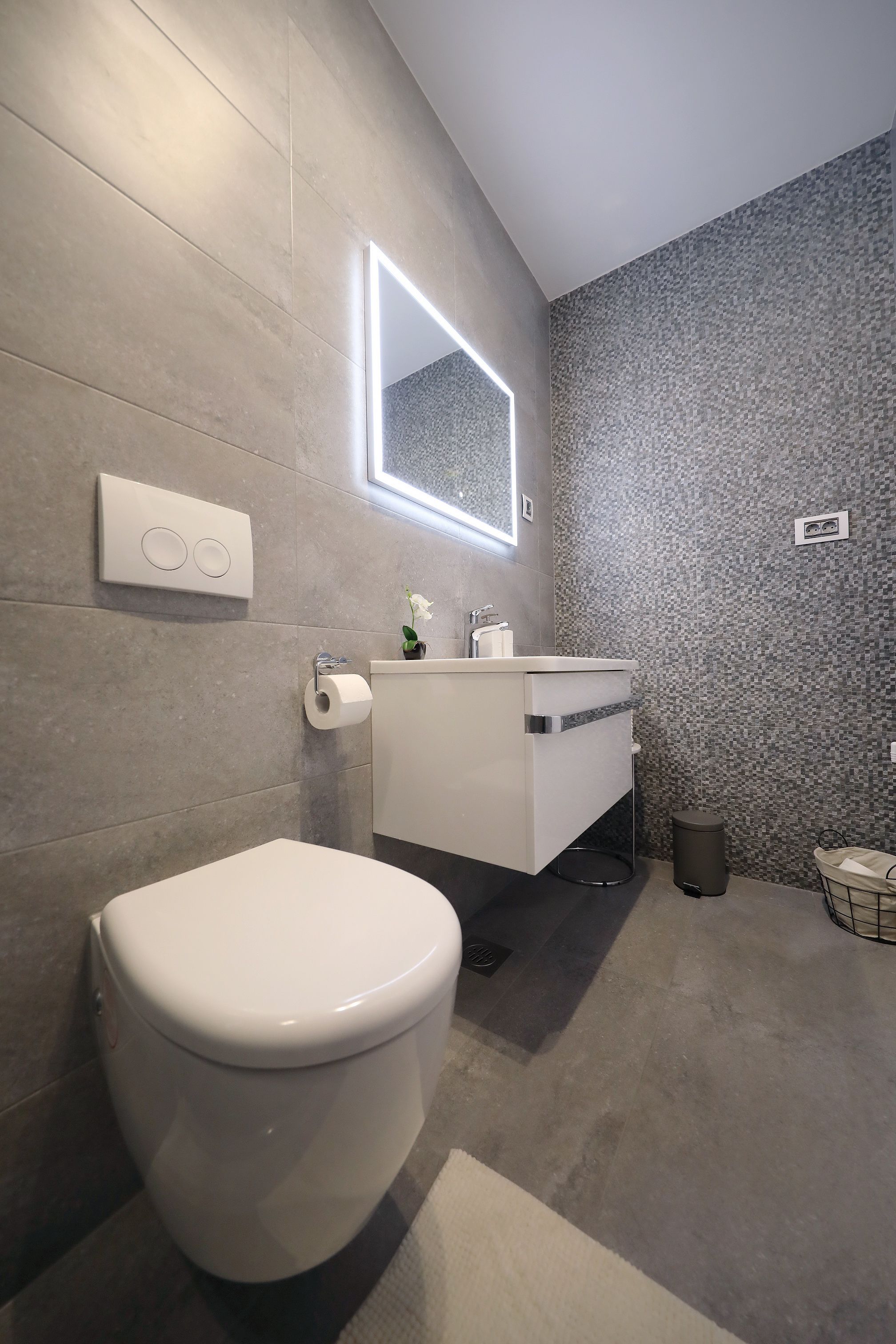 A modern bathroom with a toilet, sink, and a mirror.