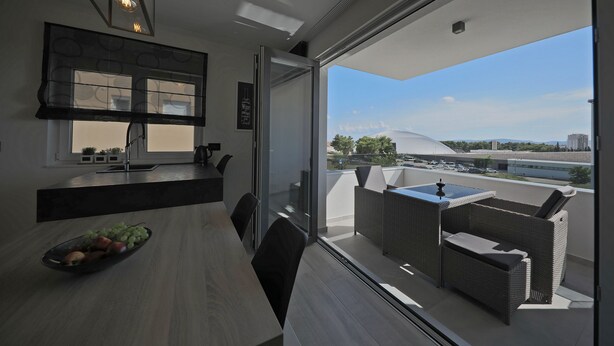 A modern kitchen with a dining area, large windows, and a view of the cityscape. - Luxury Majpruz Suites (Zadar)