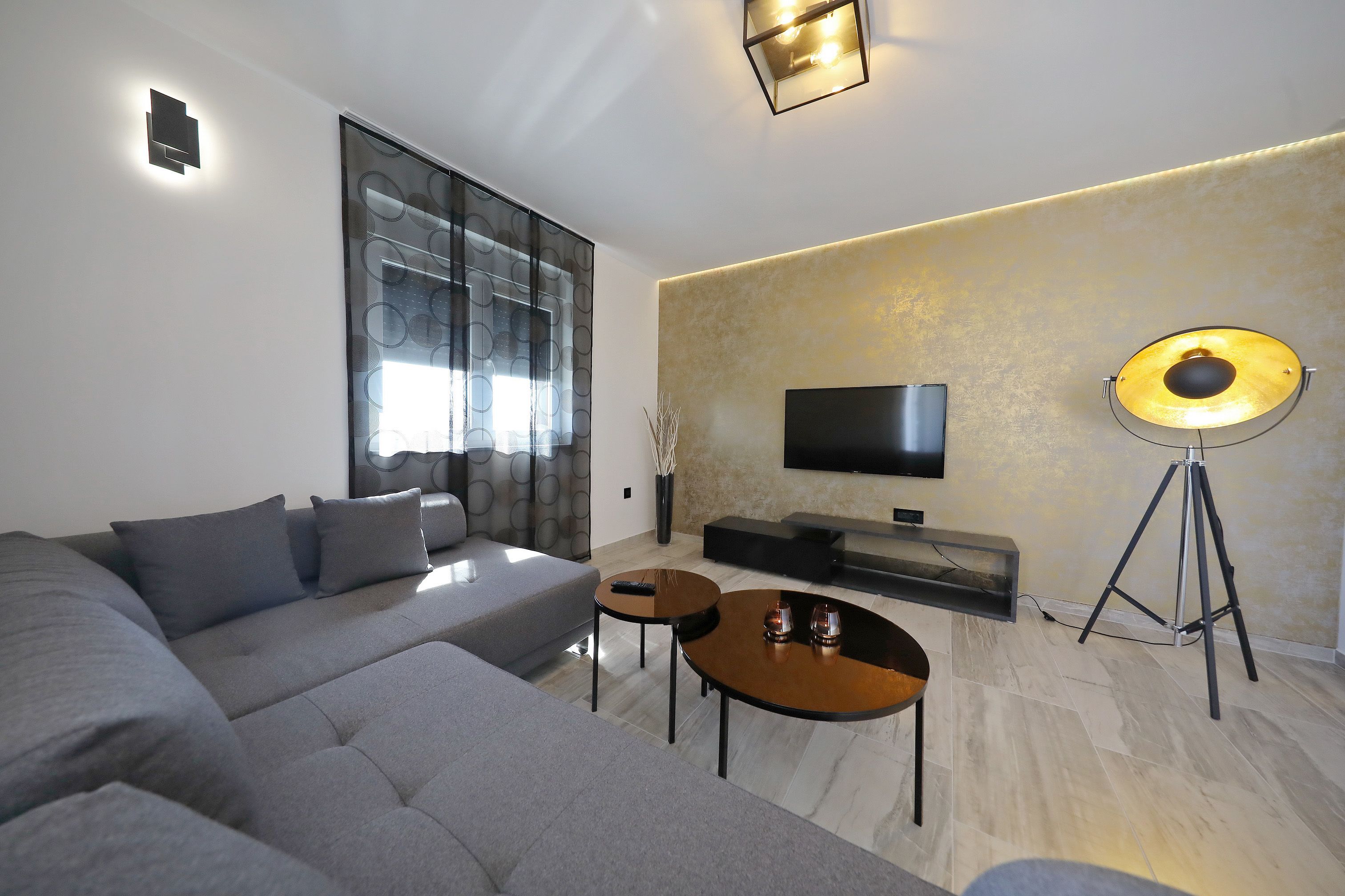 A modern living room with a sectional sofa, a coffee table, a flat-screen TV, and a floor lamp.