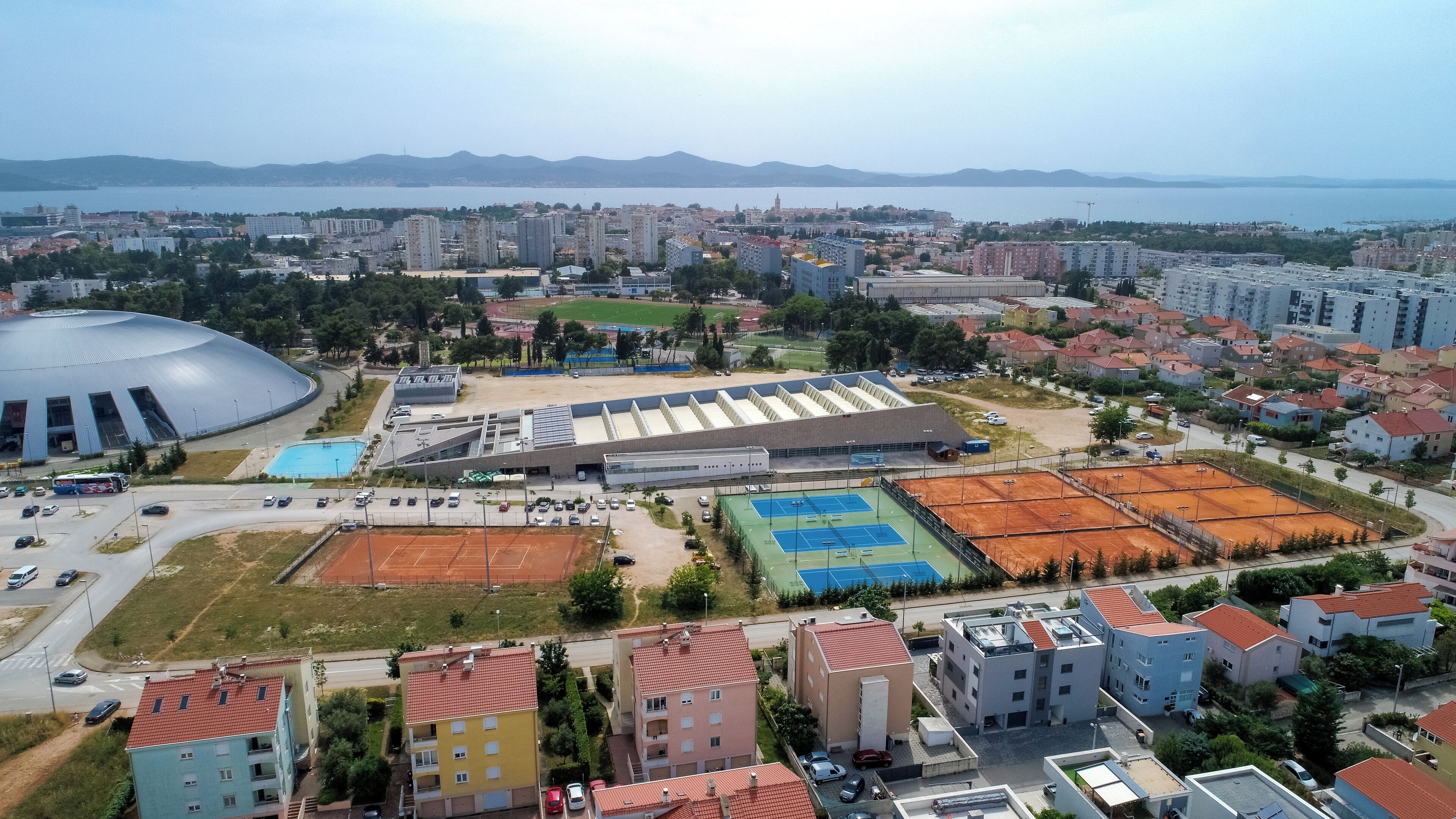 Vista aérea de un paisaje urbano con edificios residenciales, un gran complejo deportivo y un estadio.
