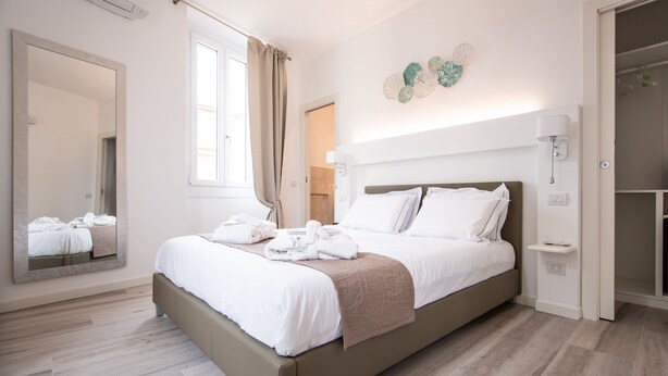 A modern hotel room with a large bed, a mirror, a wardrobe, and a decorative wall piece. - Residenza Elisa (Desenzano del Garda)